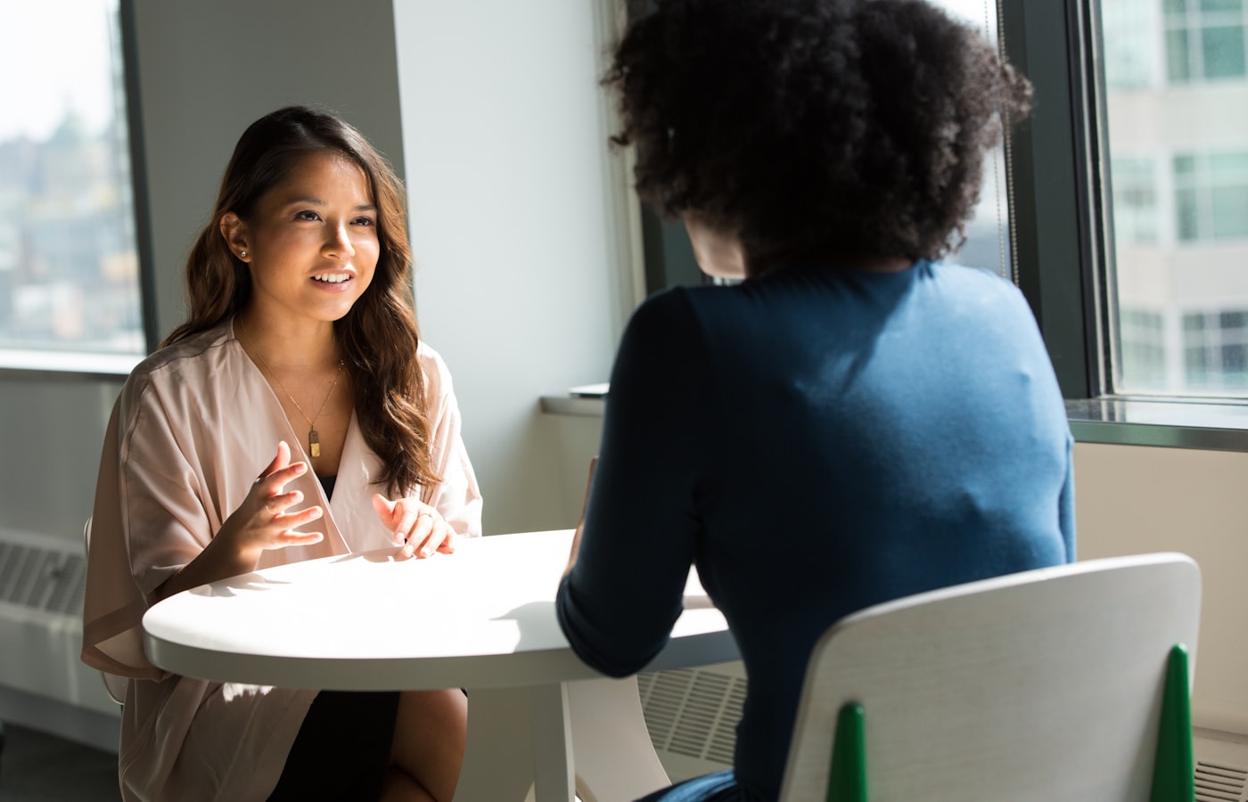 A friendly Spotto Finance broker having a relaxed one-on-one consultation with a client at a bright office table